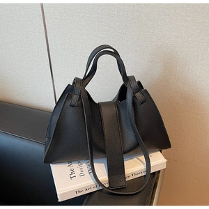 Detailed close-up of black lychee grain leather texture and trapezoidal handbag design