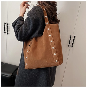 Detail view of large brown suede tote bag with stylish silver rivets on shoulder straps