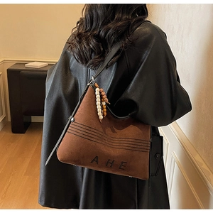 Detail of vintage brown suede tote bag with AHE lettering and bohemian beaded charm