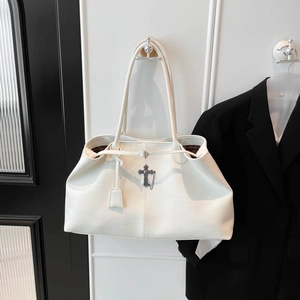 Dettaglio borsa tote in pelle bianca con croce in metallo vintage e manici lunghi a spalla