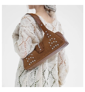Close-up of brown leather shoulder bag featuring vintage rivets and silver metal buckle