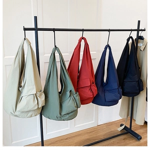 Detail view of lightweight large capacity shoulder bags in multiple colors on a display rack