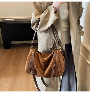Gros plan d'un sac cabas en daim marron avec bandoulières en cuir et détails dorés