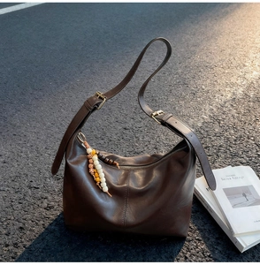Détail du sac hobo en cuir marron foncé avec boucle en métal et breloque en perles colorées