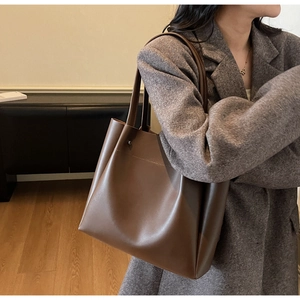 Brown leather tote bag styled on a grey blazer for a professional business casual look
