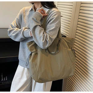 Detailed view of olive nylon tote bag featuring adjustable drawstring and knotted handles