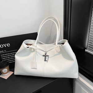Dettaglio della borsa tote bianca in pelle martellata con ciondolo a croce vintage