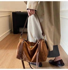 Détail du sac en daim marron avec poignées en cuir et garnitures métalliques dorées