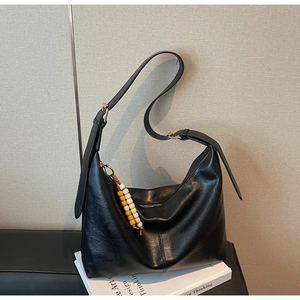 Détail du sac hobo noir avec breloque vintage perlée et boucles de sangle réglables