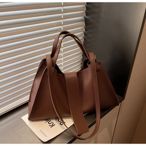 Detail of high-quality brown pebbled leather texture on a stylish commuter dumpling bag