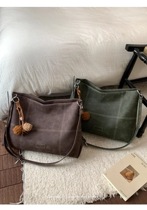 Close-up of matte tote bags with contrast stitching and decorative plush pendants