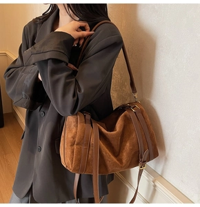 Détail du sac Boston en daim caramel montrant la texture et la bandoulière réglable