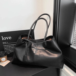 Dettaglio borsa shopper nera in pelle PU con ciondolo a croce e trama stropicciata