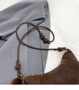 Vue détaillée du sac matelassé marron avec bandoulière en corde et charmant pompon en peluche