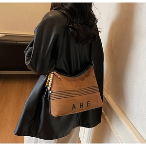 Close-up of vintage brown suede tote bag with black embroidery and bohemian beaded charm