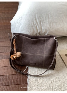 Detailed close-up of dark brown matte leather tote bag with white decorative stitching