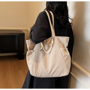Detail of a beige large tote bag showing nylon texture and stylish rope handles