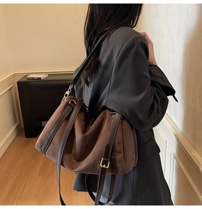 Détail d'un grand sac fourre-tout vintage en daim marron porté à l'épaule pour le quotidien