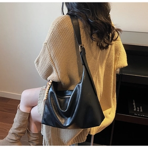 Vue détaillée du sac hobo en cuir noir avec breloque perlée beige et fermeture