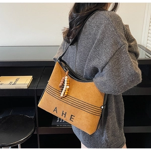 Detail of vintage brown suede tote bag with AHE logo and colorful wooden bead accessory