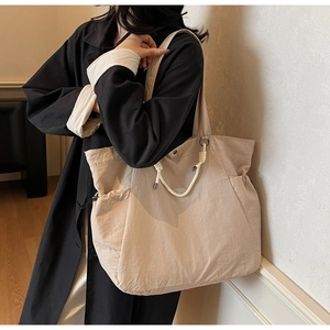 Detail of light khaki tote bag showing rope handles and adjustable drawstring side pocket