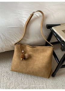 Detailed close-up of textured tote bag with cross-stitch design and pompom pendant