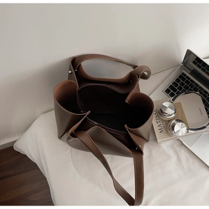 Top view of brown leather tote bag with internal zipper divider on an office desk