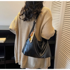 Vue détaillée du sac hobo noir avec pendentif décoratif en perles de bois ethniques
