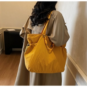 Yellow large capacity tote bag with drawstring details worn with a beige trench coat