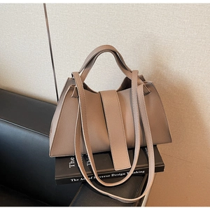 Detailed view of taupe lychee leather texture and trapezoidal design of the shoulder bag