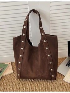 Large dark brown suede tote bag with silver metal studs shown in a casual office setting