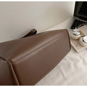 Detail view of the brown tote bag's base with precise stitching and leather texture