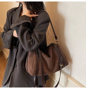 Détail du sac boston en daim marron foncé avec lanières en cuir et ferrures dorées