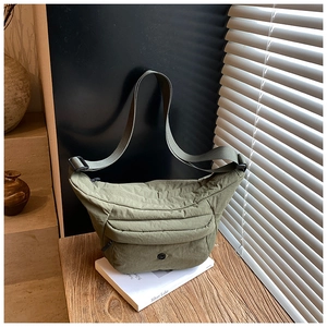 Olivgrüne Nylon-Halbmondtasche auf Holztisch mit Staufächern und verstellbarem Gurt