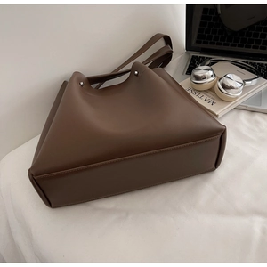 Close-up of brown matte leather tote bag with laptop and books for a commute look