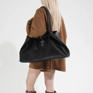 Dettaglio della borsa tote in pelle nera con ciondolo a croce argento e doppi manici