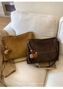 Detailed close-up of ginger and brown suede tote bags with quilting on a white sofa