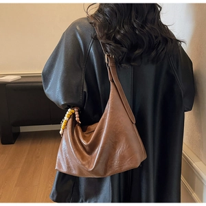 Détail du sac hobo marron vintage avec finition texturée et charme en perles