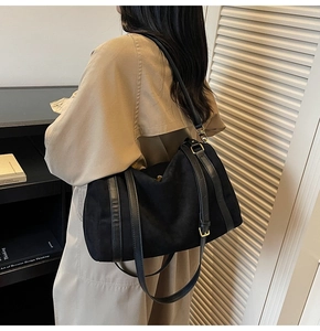 Détail du sac bandoulière en daim noir avec bandoulière en cuir et boucle dorée