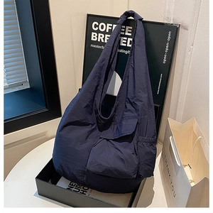 Detail of navy blue nylon tote bag with pleated texture and elastic side pocket storage