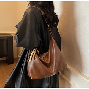 Détail du sac hobo marron vintage avec perles en bois tricolores sur la bandoulière