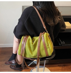 Détail du sac seau en daim vert avec lanières en cuir marron et texture mate lisse