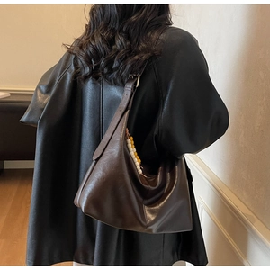 Détail du sac hobo vintage en cuir marron avec breloque perlée et texture souple