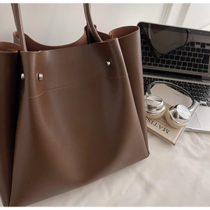 Macro detail of brown leather tote bag with silver studs and premium textured finish