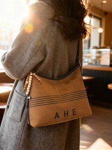 Brown suede tote bag with embroidery and wooden bead tassel in a warm cafe setting