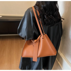 Brown leather trapezoid shoulder bag featuring asymmetrical design and stitching details