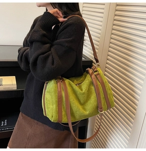 Détail du sac polochon en daim vert avocat avec finitions en cuir marron et fermeture éclair