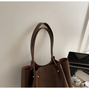 Detail view of deep brown minimalist tote bag with silver rivets and commuter style