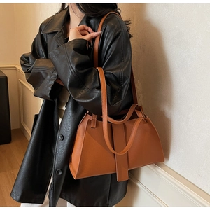 Close-up of orange-brown pebble leather shoulder bag with buckle detail on a model