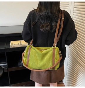 Détail d'un grand sac en daim vert avec bandoulières en cuir marron porté par un mannequin